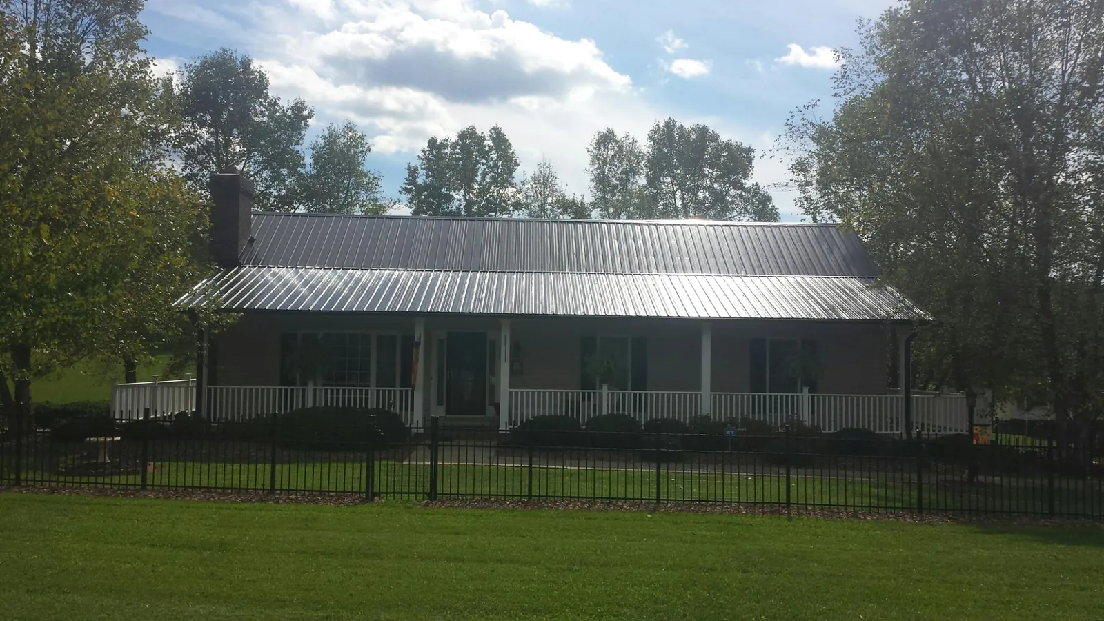 Gray metal roof on a brick ranch with a full width front porch — Gutter Guard Installation work by our crew in Atlasburg