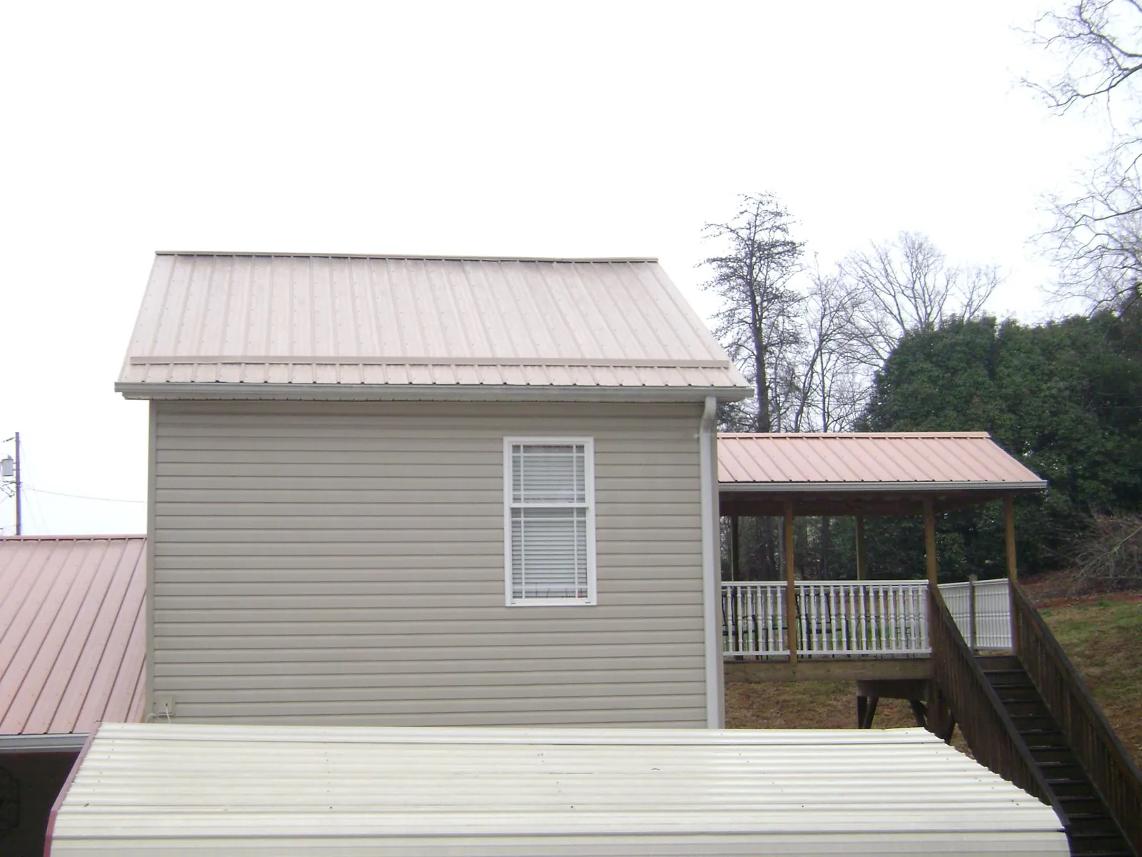 Tan metal roofs on a two story addition and attached porch, from a Roof Replacement job in Atlasburg