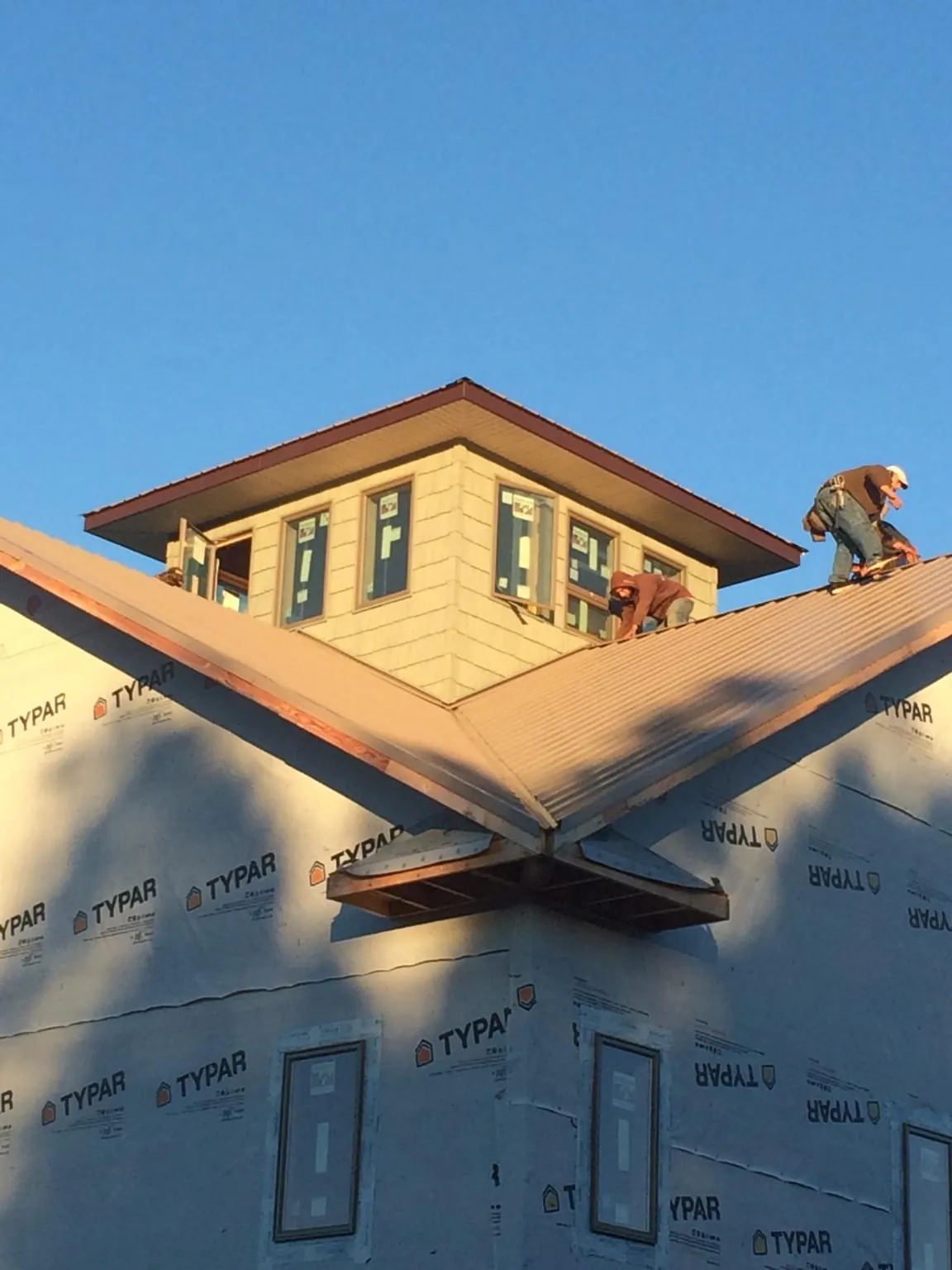 Roofers working around a rooftop cupola on a new metal roof at sunset — Roof Waterproofing in Atlasburg by Roofing Brothers